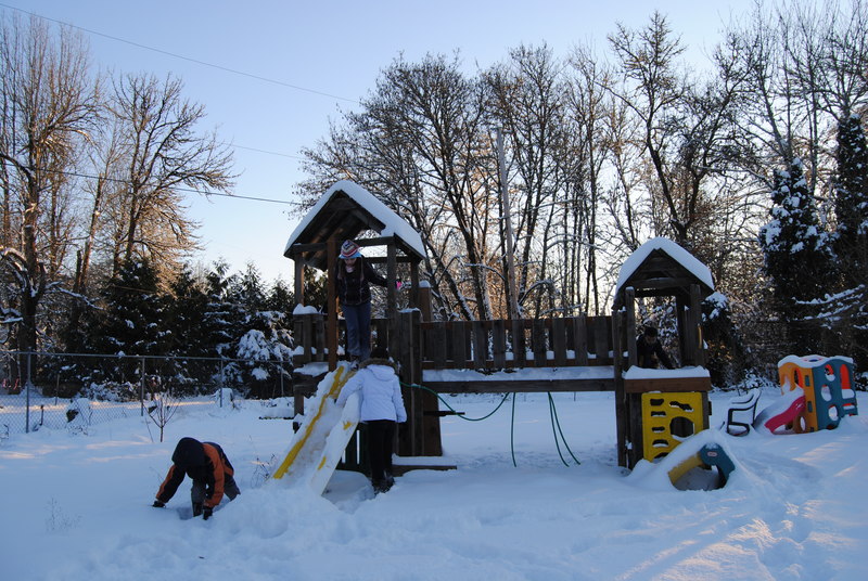 Play structure and kids playing in the snow.