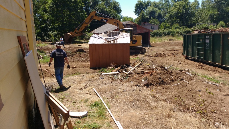 We are clearing the western parking lot. One step is removing the old brown shed. Joseph walks nearby.