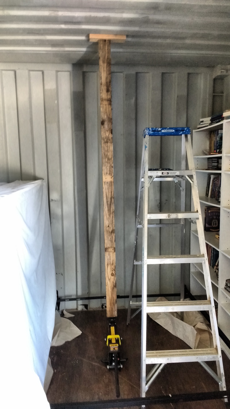 Here we see the block of wood being held in place by a 7-foot 2x4 and a car jack. This is where the Glamping chandelier will go.