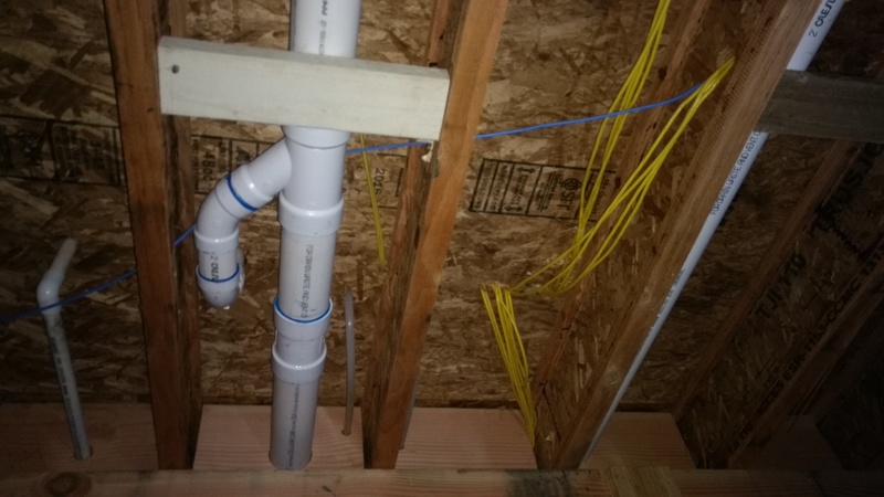 Network wiring disappearing into the ceiling of the garage, and sewer line drain pipes.