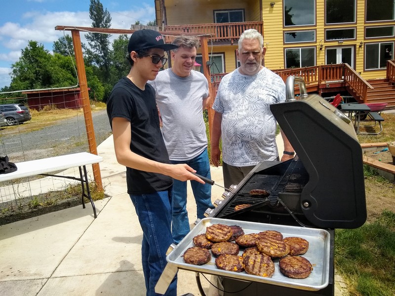 Family Gathering: Mikey cooks burgers on the grill.