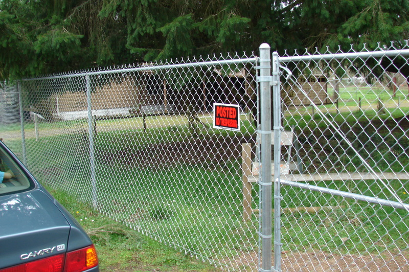 New chain link fence along side road. Carport.
