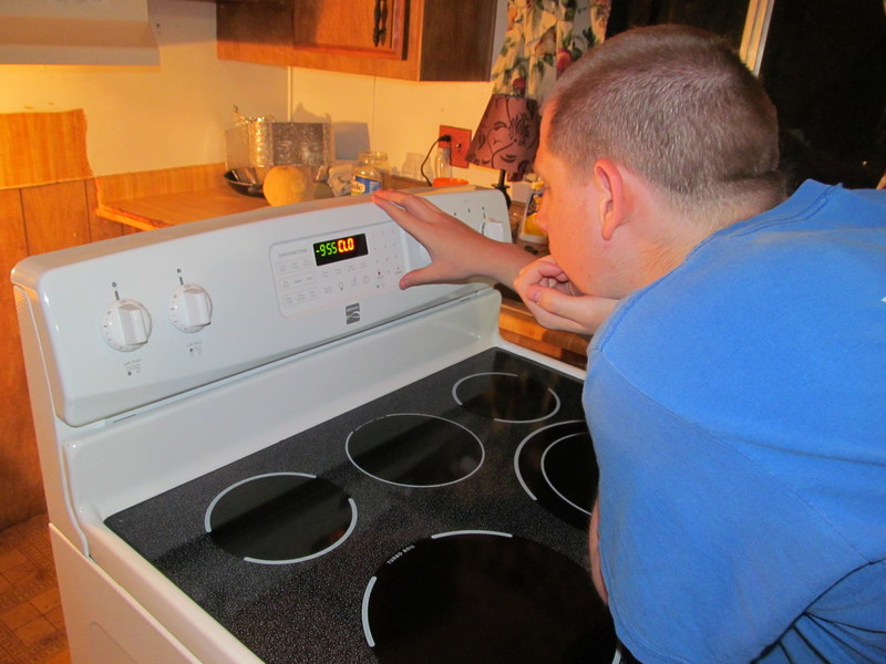 Isaac figuring out how to set the stove clock so that the stove will start.