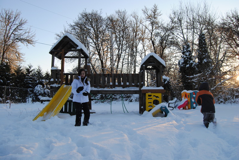 Play structure and kids playing in the snow.