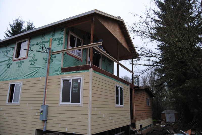 Railings for the balcony are starting to take shape. The siding has been added to the west side of the old house.