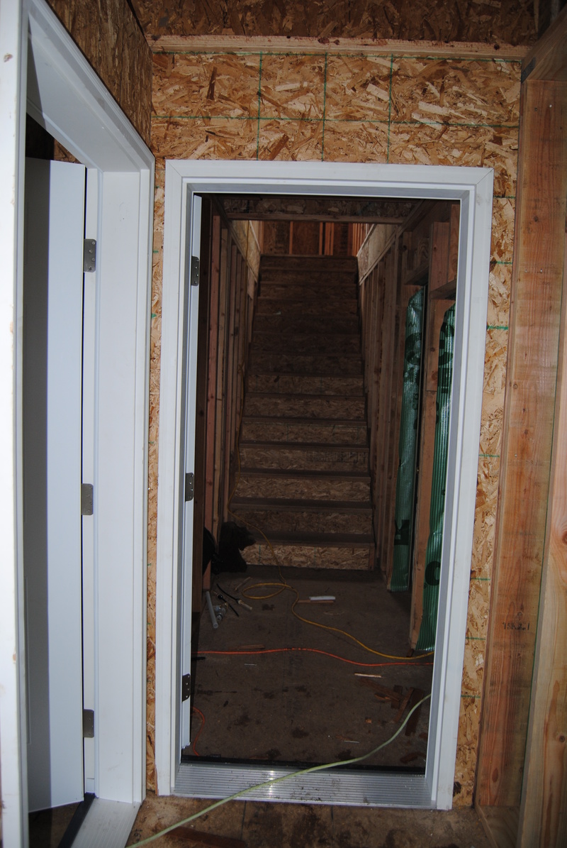 View of the west door into the addition. Wrong door, with hinges on the wrong side. Will be fixed. Also view of the door into the equipment room, and view up the stairway.
