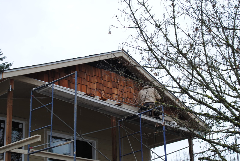 Worker adding shingles to the west face of the addition.