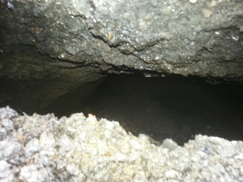 Culvert sinkhole. Closeup of the gap under the remaining asphalt.