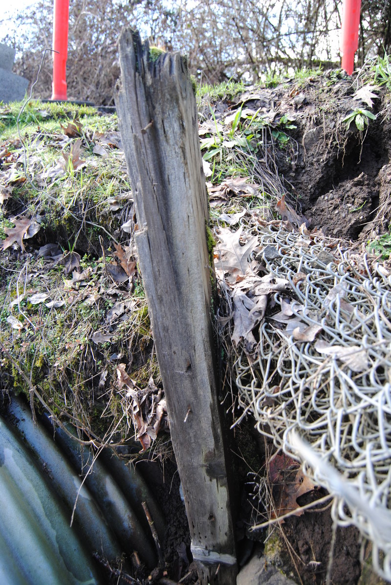Culvert, near the opening. Post may be intended to slow the erosion of nearby soils.