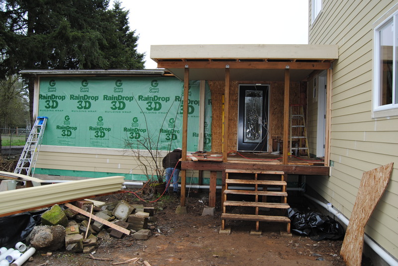 The front porch with siding being installed to the left (east).