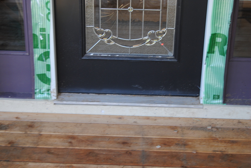 Front entrance. Metal door sill. Green building wrap.