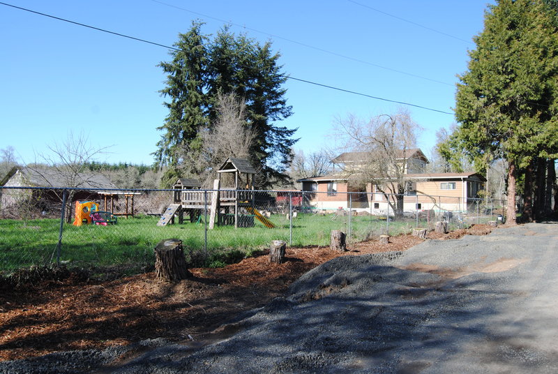 View of the south face of the house and of the play area from Rosewold Lane. Also gravel on the roadway.