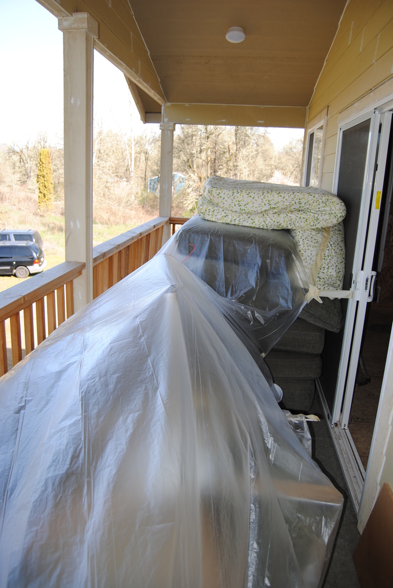 Lois furniture out on the west balcony, covered, to make way for insulation and drywall.
