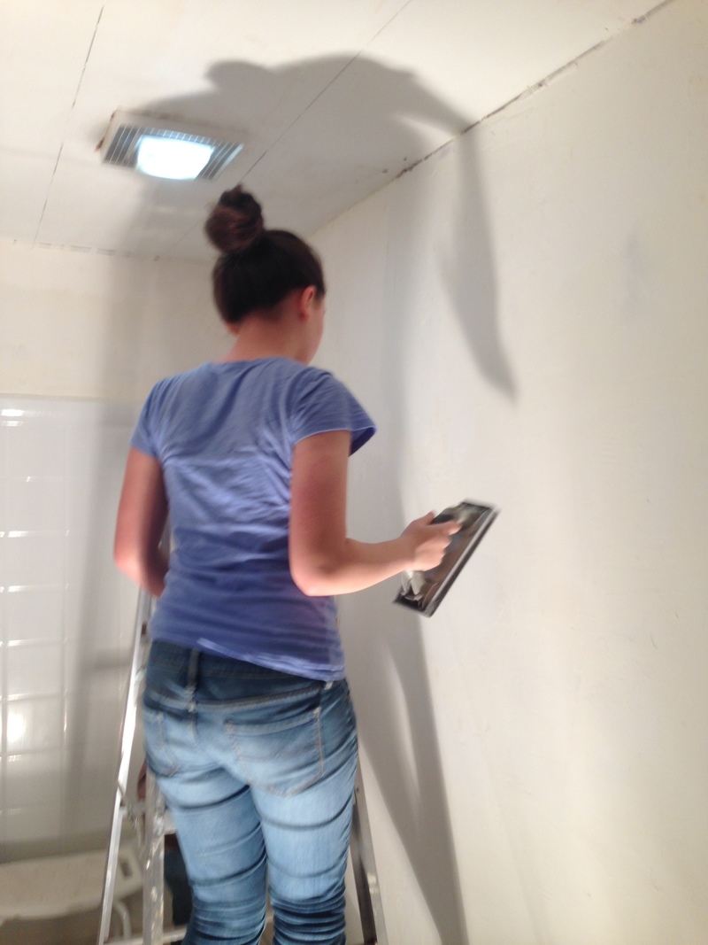 Shannon sanding the bathroom wall.