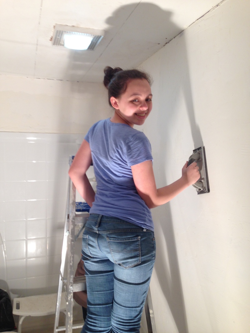 Shannon sanding the bathroom wall.