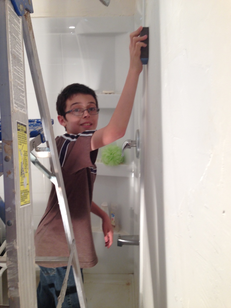 Mikey sanding the bathroom wall.
