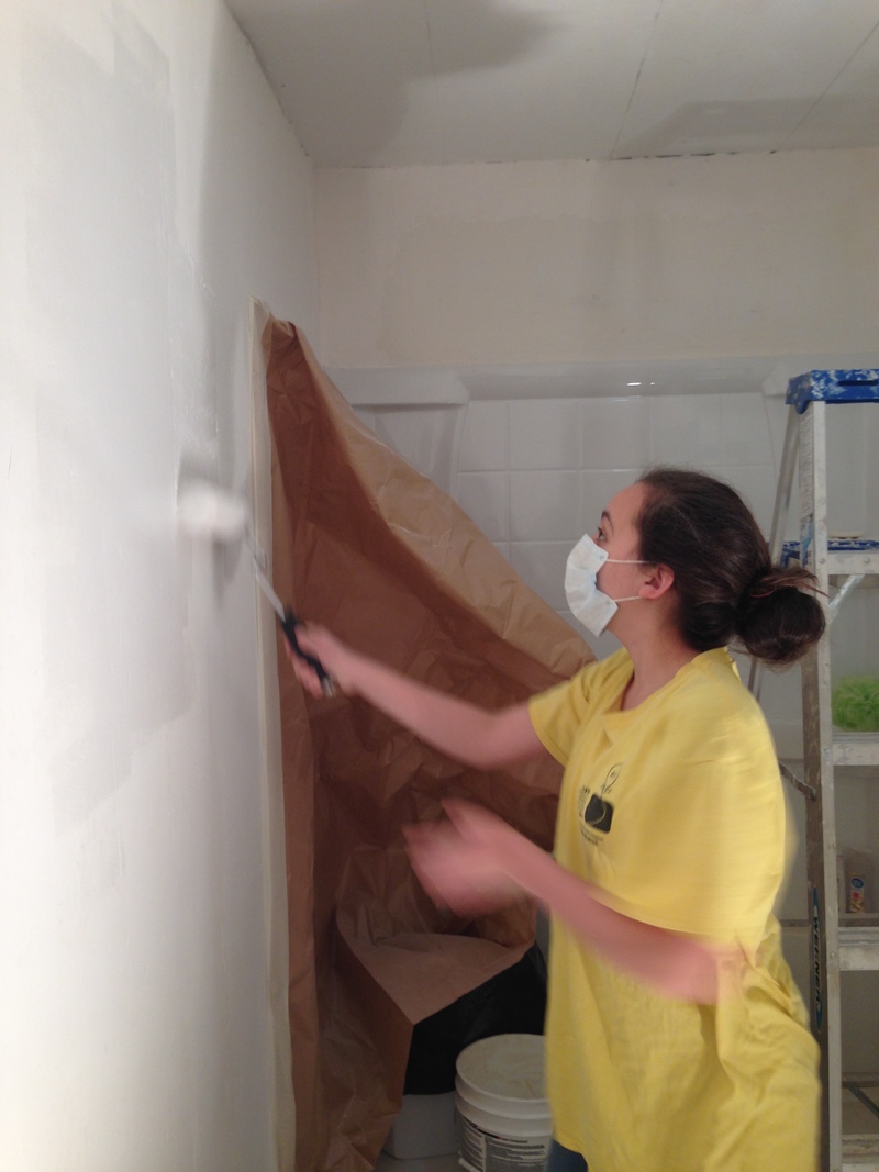 Shannon painting the bathroom wall with primer.