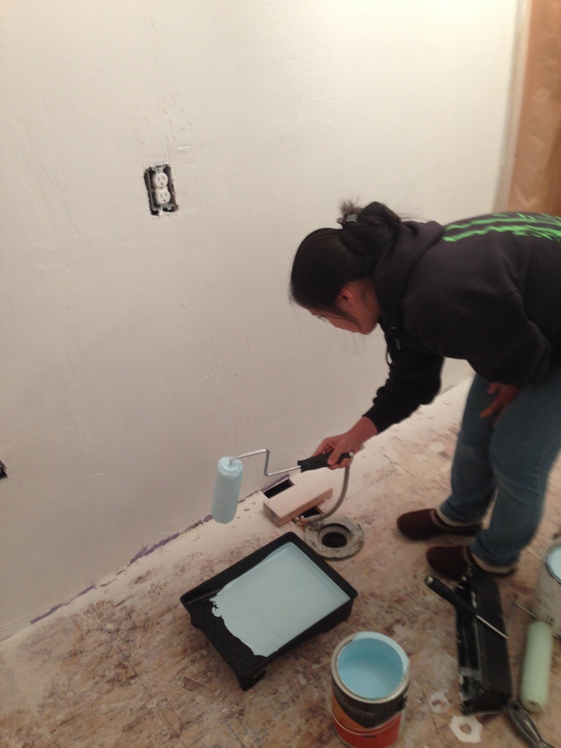 Akiko painting the bathroom wall with light blue paint.