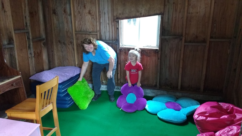 Lois and Kekoa put the finishing touches on the new Club House. Pillows and futons on top of grass-like carpet, on top of plywood, on top of gravel that has been raked smooth. The club house occupies the southwest corner of the Red Shed.