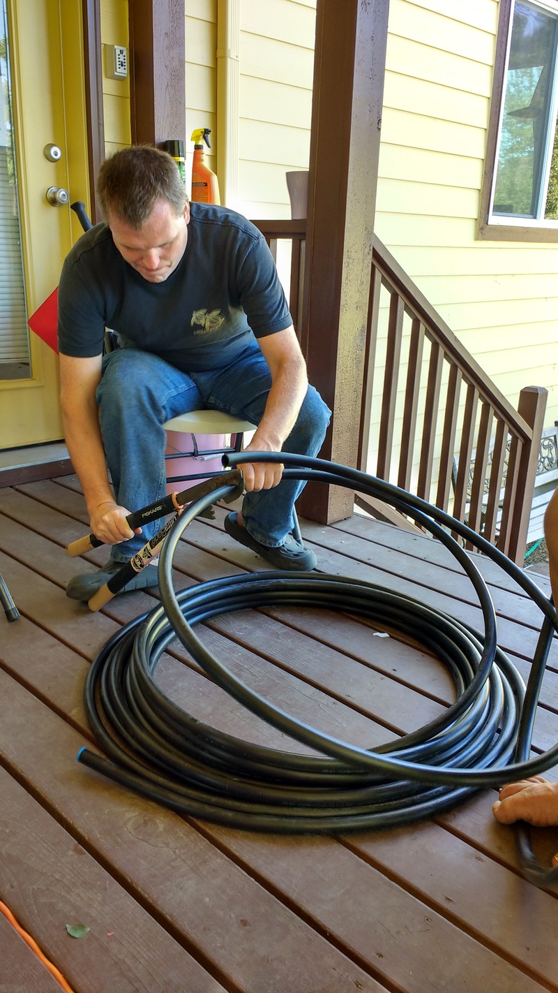 Joseph cuts off a length of drip irrigation hosing.