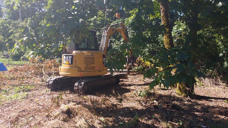 The small excavator is removing fence posts and a tree limb.