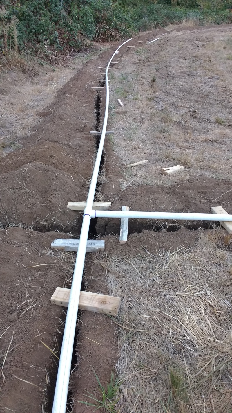 Chopped up pallet boards are being used to hold the PVC above the trench until we are ready to lower it into place.