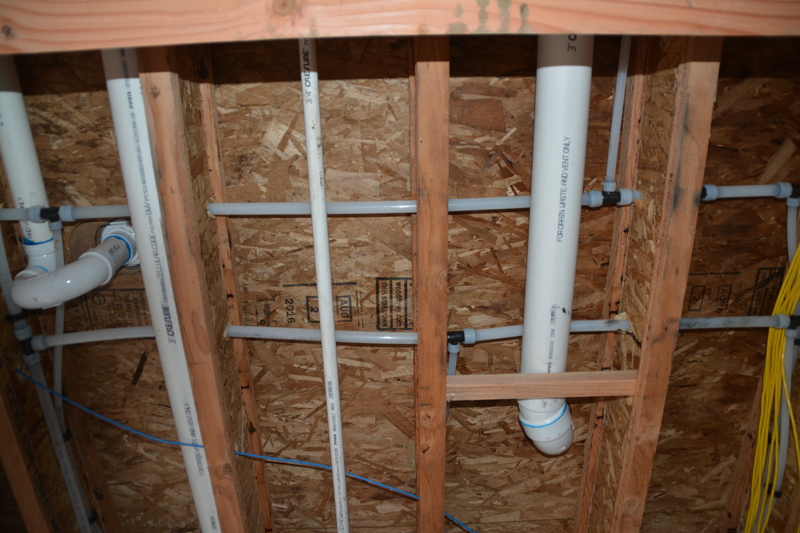 garage inside north ceiling showing shower drain (left) and shower toilet (right).