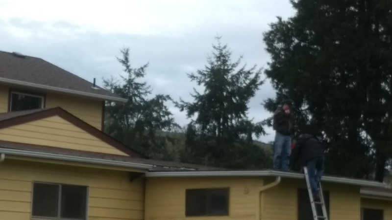Men on the roof cutting a hole.