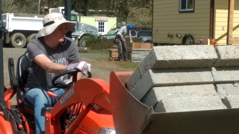 Joseph moving pavers from under the old manufactured home to the new Greenhouse Patio.