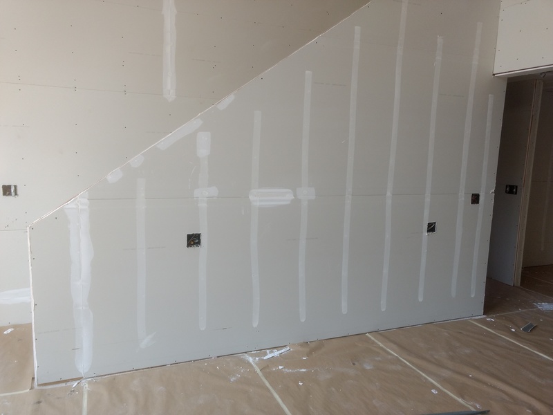 Day 1 of mudding, covering the screw heads and other sheetrock blemishes. Now it has to dry. Great room stairway.