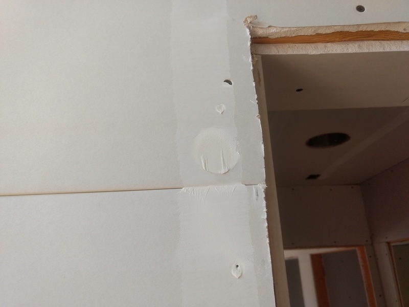 Mudding near a doorway, filling in holes. After this they will sand it down and then fill things again.