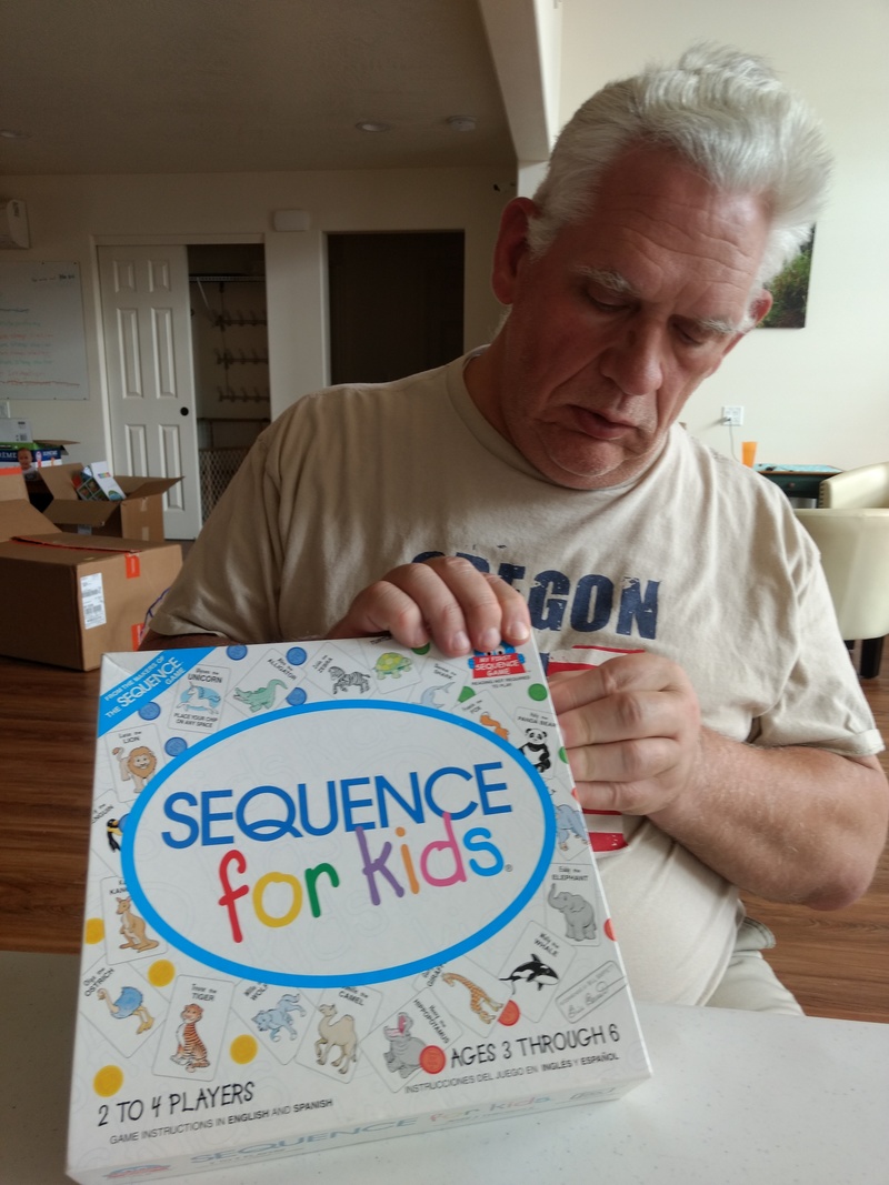 Don peels the price sticker off the side of a new game, "Sequence for kids." We played a round and Lois won.