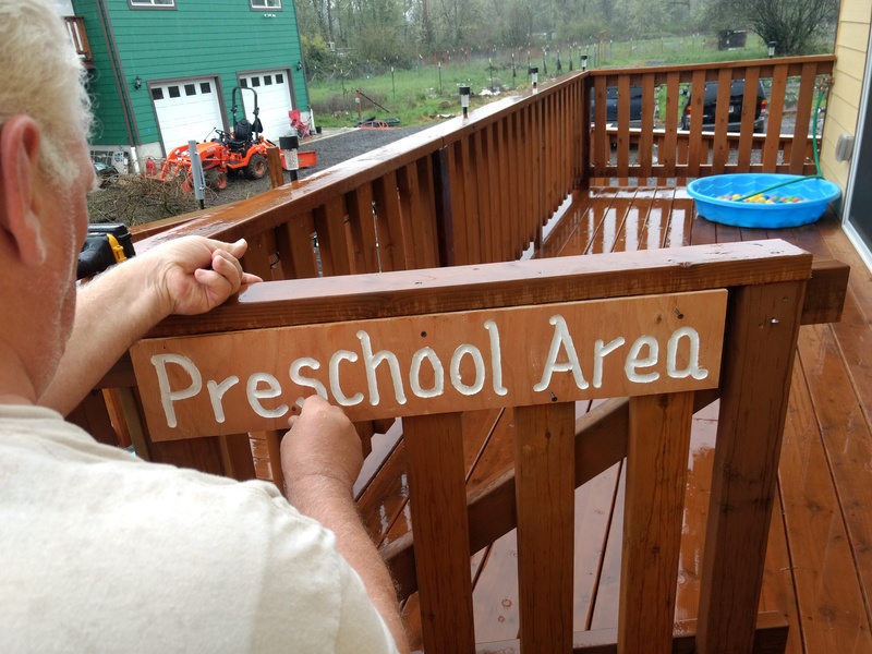 Don attaches the Preschool Area sign.