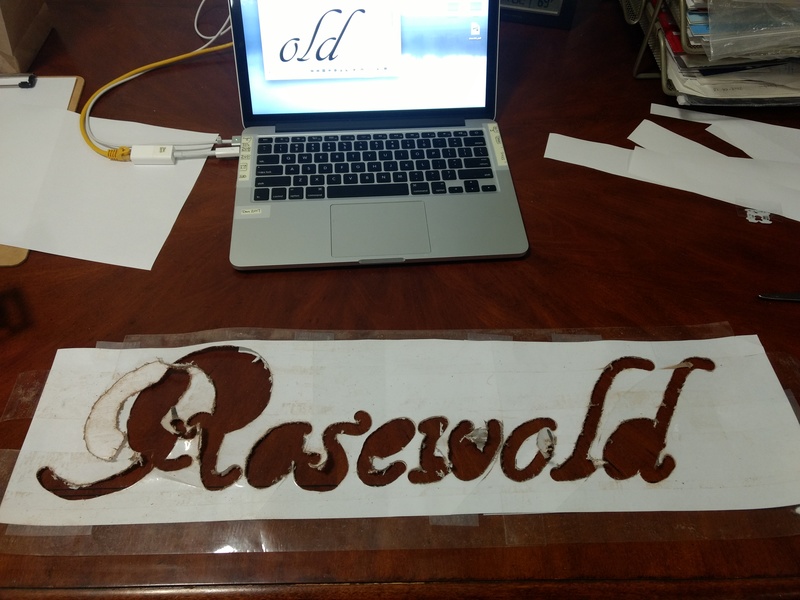 I printed Rosewold in our favorite font for it, at 540pt size, and taped together four sheets of paper. Then I covered the paper in box tape so I could run the router on it.