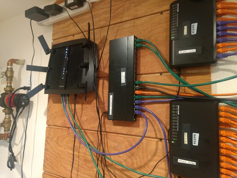 New GS316 Gigabit Ethernet Switch, surrounded by R8000 Nighthawk (left) and two 24-port 10/100 Netis switches (right).