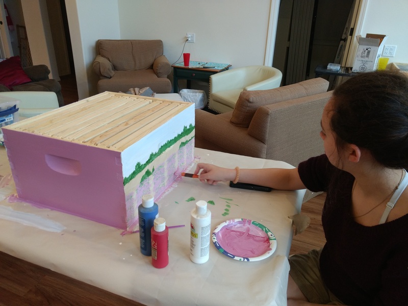 Shannon paints a beehive.