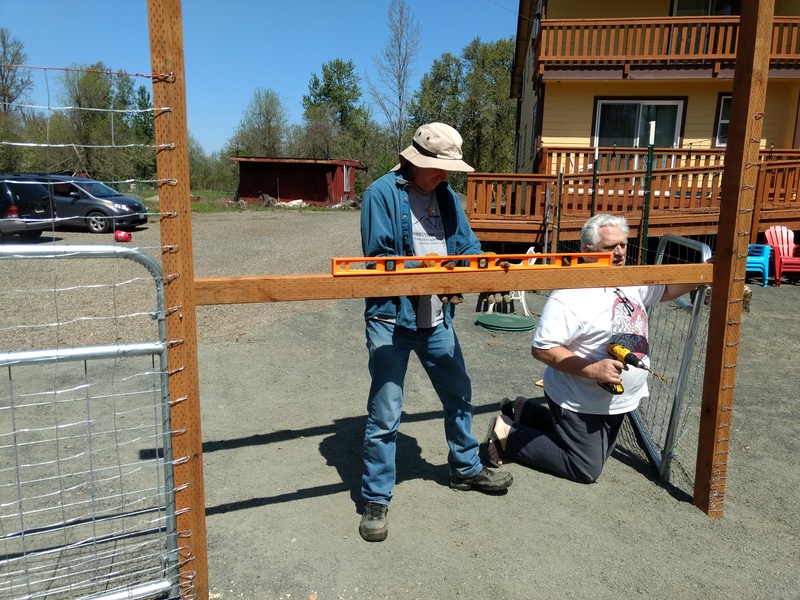 Joseph and Don use a construction level to make sure the hinges on the gate are at the same height.