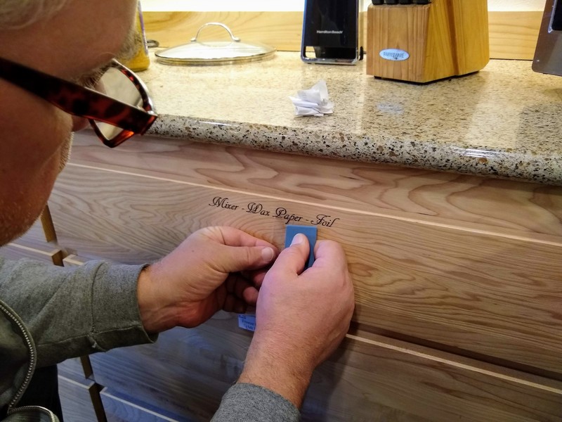 Don installs lettering on kitchen drawers.