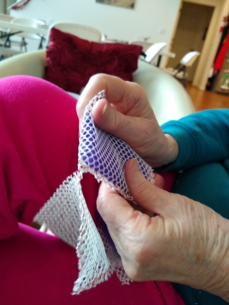 She puts two kinds of net together and sews them shut.
