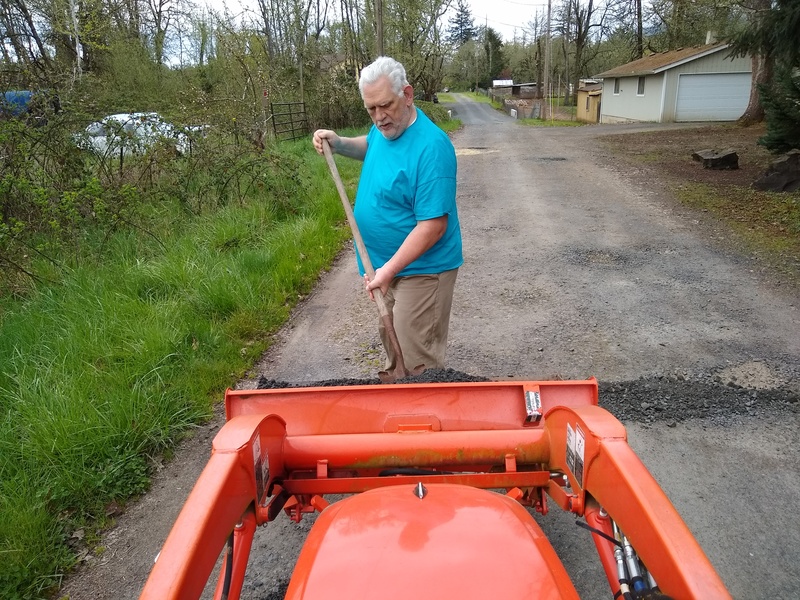 Don is filling potholes with gravel while Lois drives the tractor.