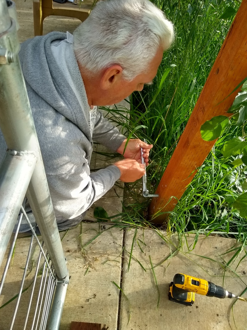 Don works to attach the new six-foot gate on the guest house south sidewalk.