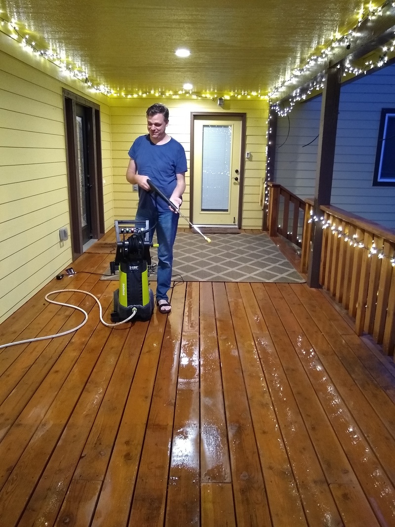 Joseph power-washes the front entry deck.