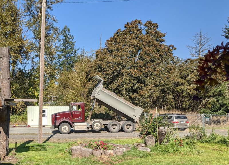 The truck is spreading gravel in the north parking lot.