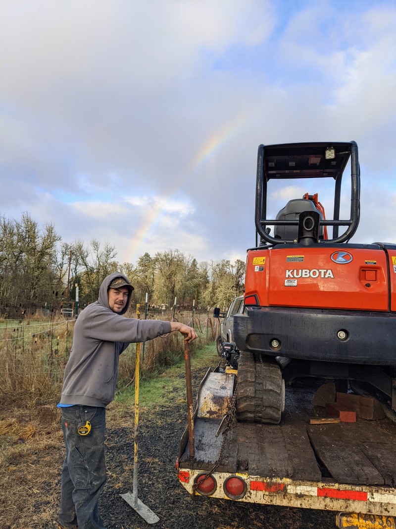Dustin poses with his excavator. He is our pot of gold. (Notice the rainbow?)