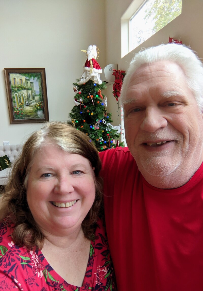 Santa and Mrs Claus, dressed in red, in front of our Christmas Tree.