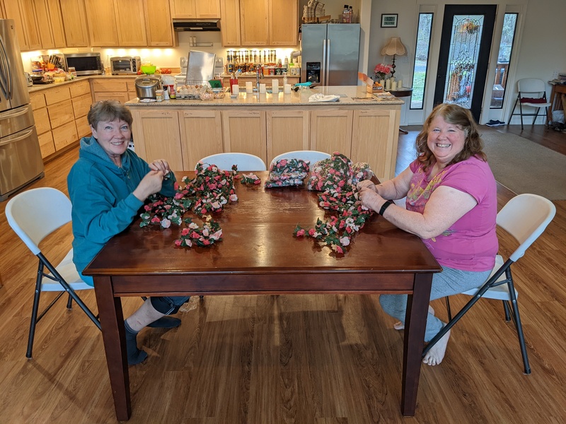 Laura and Lois stringing roses together.