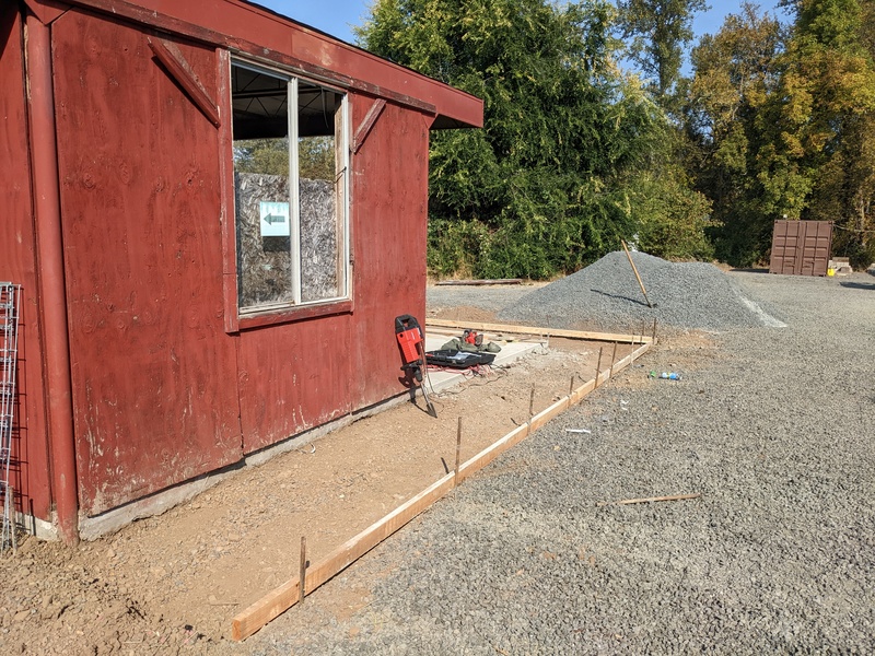 Sidewalk around red shed is framed.