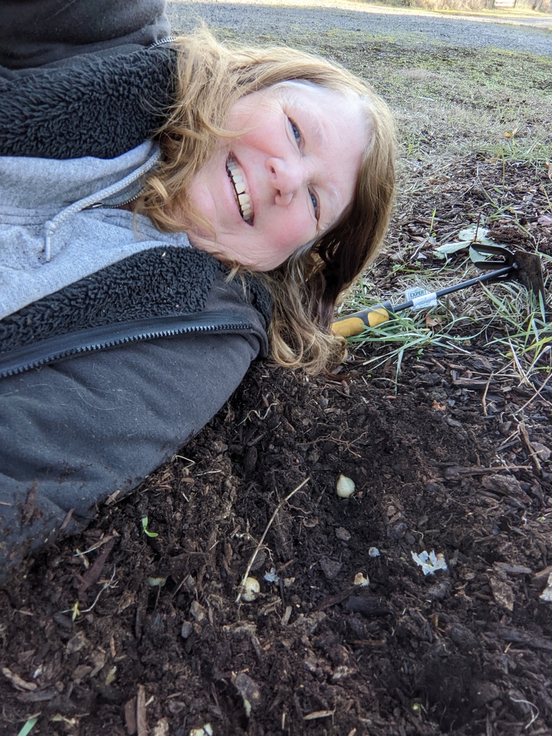 Lois is laying down on the job, as she stretches to plant bulbs.
