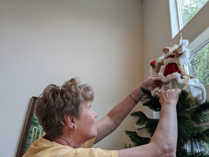 Laura adjusting the angel at the top of the tree.