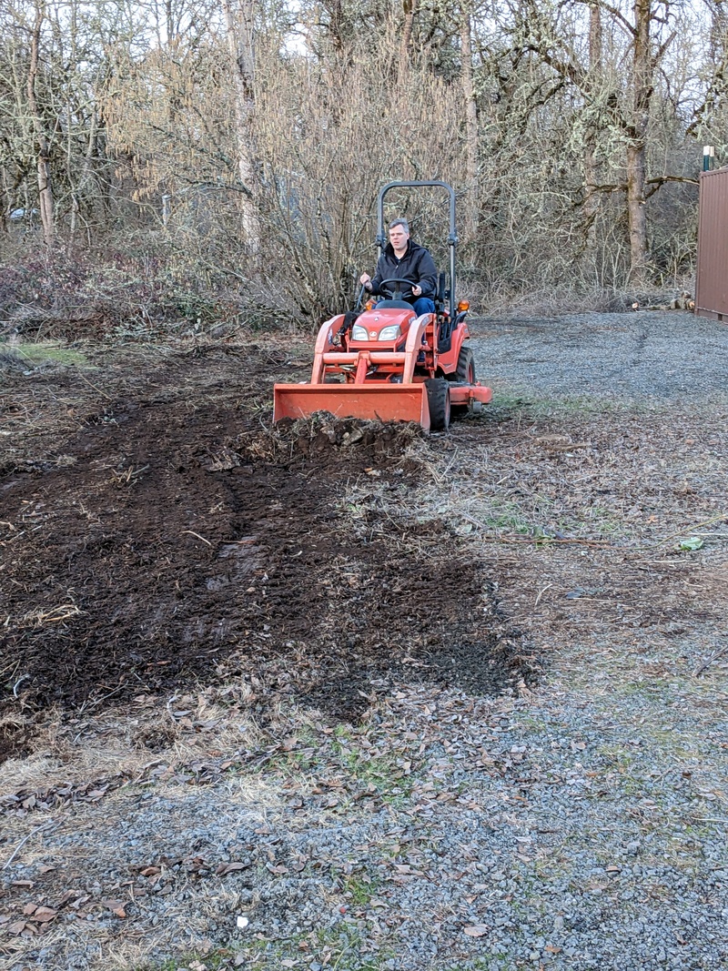 Joseph levels the ground where a new parking area will be created under the newly trimmed tree.